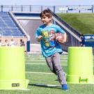 Child runs with football around trash cans