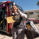 Gabriela Jimenez holds golden ticket near red Unitrans bus.